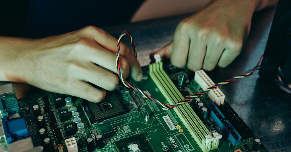 Person assembling computer motherboard with colorful wires, showcasing technology and engineering.